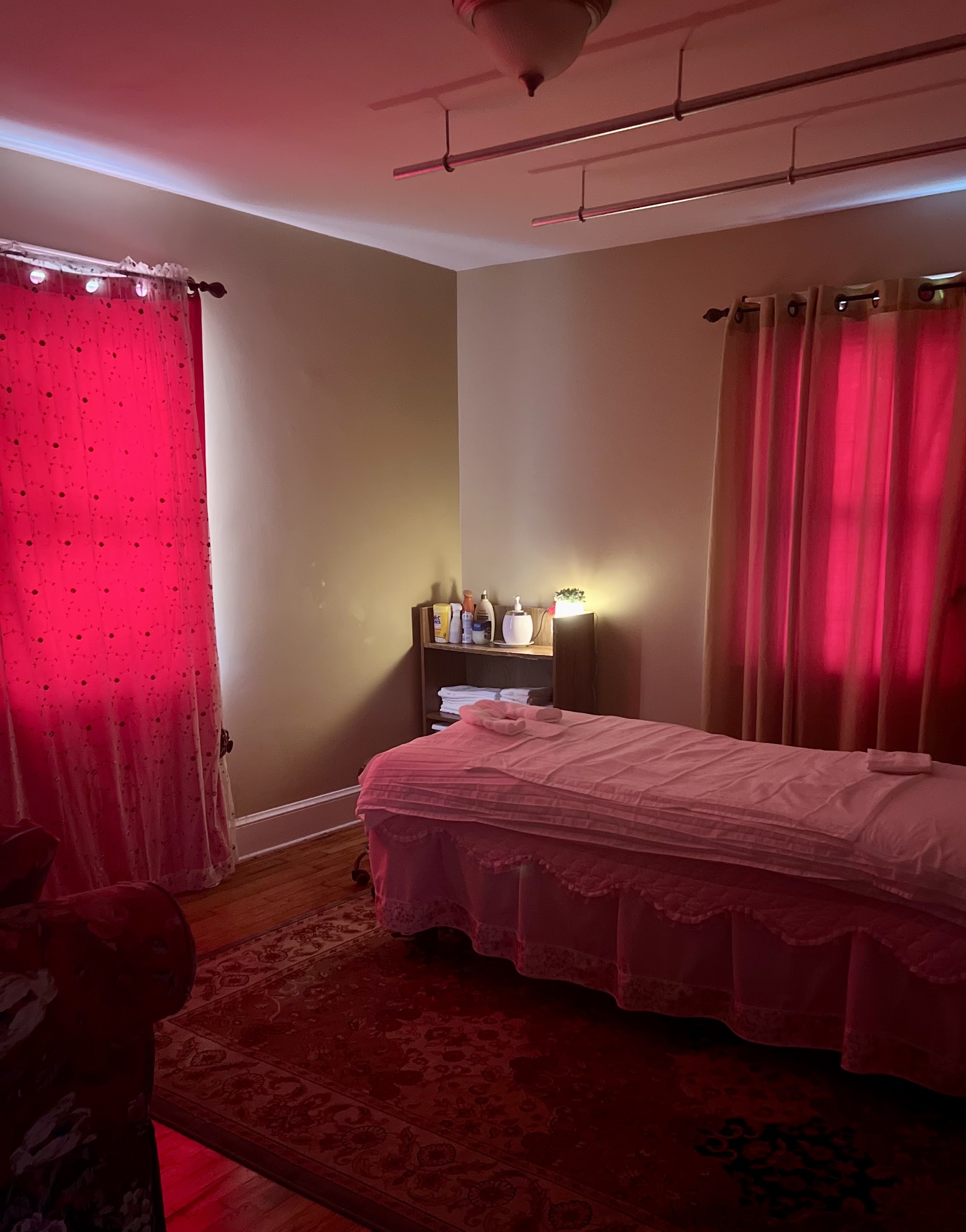 A treatment room with a made-up massage table, warm lamp and soft curtains