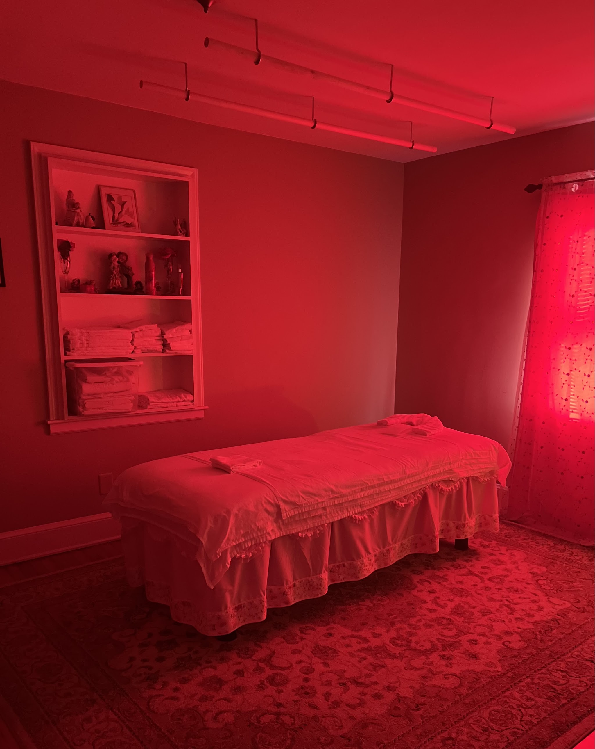 Our treatment room under soft red light, with fresh linens on the shelf